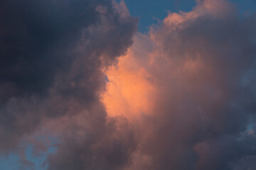 Fototapeta premium Cloud landscape. Pink and brown summer cumulus clouds on a blue sky during sunset. Wallpaper. Background.