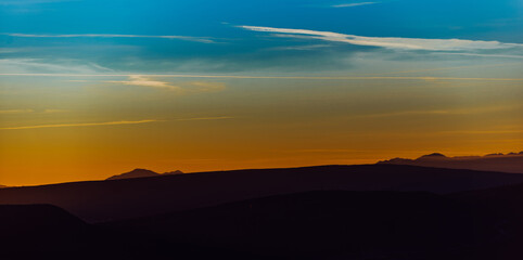 Capturing the breathtaking beauty of a vibrant orange and purple sunset over a majestic mountain during a serene summer evening