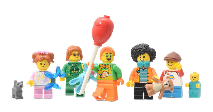 Lego minifigures of clown in purple cup and children with toys on the street parade or carnival. Editorial illustrative image of carnival.