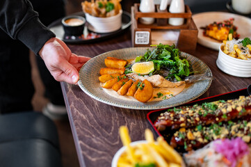 waiter hand hold Fried dorado fish with Potato country style fried and sauce on plate