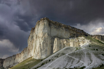 Mountainous, rocky landscape and White Rock peak against a stormy sky.