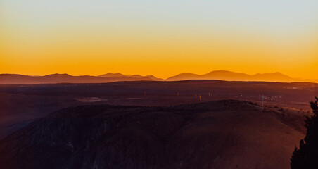Capturing the breathtaking beauty of a vibrant orange and purple sunset over a majestic mountain during a serene summer evening