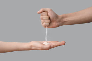 Sand pouring from male hand to female on grey background. Time concept