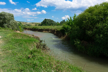 Landscape, narrow mountain river with emerald water surrounded by trees.