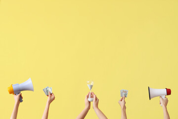 Female hands holding hourglass, money and megaphones on yellow background