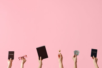 Female hands holding hourglass, passports, money and law book on pink background