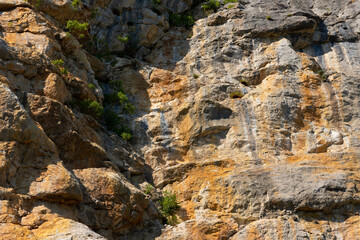 A sheer wall of red-gray color on a rock in the mountains, the texture of natural stone. Active sport. Background, stone texture. soft focus