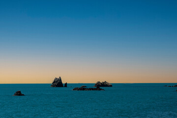 Fototapeta premium Seascape with lonely wild black rocks in the water at dawn. selective focus