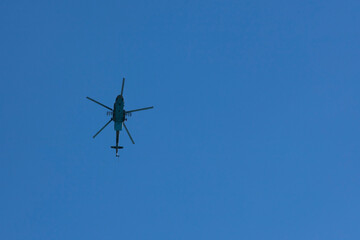 Military Russian helicopter flies in the blue sky. Bottom view.
