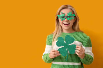 Cute little girl in decorative glasses with clover on yellow background. St. Patrick's Day...