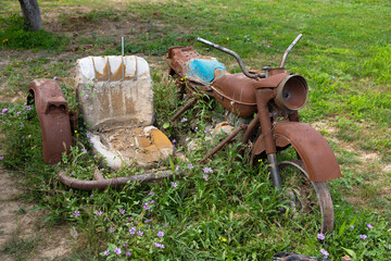 An old, rusty motorcycle with a sidecar stands on a green grass.