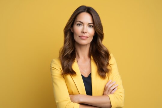 Portrait of a confident businesswoman standing with crossed arms over yellow background