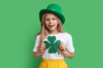 Cute little girl in leprechaun hat with clover on green background. St. Patrick's Day celebration