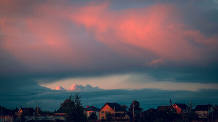 Stormy sky with dramatic clouds from an approaching thunderstorm at sunset. Stormy sky over the village.