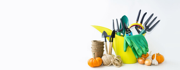 Banner on a light table background - garden tools: spatula, rake, green watering can, gloves,...