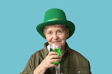 Senior woman in leprechaun hat with glass of beer on blue background. St. Patrick's Day celebration