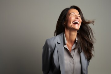 Happy business woman laughing and looking up on grey background with copy space