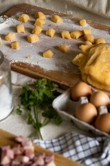 Ingredients like eggs, flour, pancetta and wine on a wooden surface for recipe preparation of gnocchi pasta