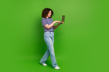 Full size profile portrait of cheerful girl use netbook texting walk empty space ad isolated on green color background