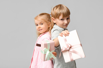 Cute little children with gift boxes on grey background. International Women's Day