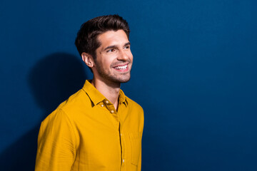 Photo portrait of attractive young man look empty space cheerful smile wear trendy yellow clothes isolated on dark blue color background