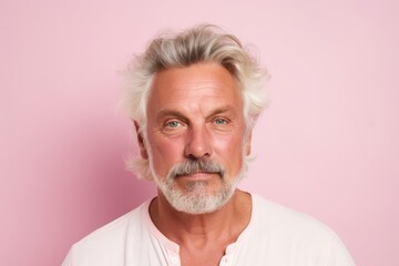 Portrait of senior man with grey hair and beard on pink background