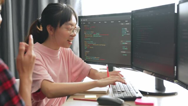 Slow motion back end software developer engineer for computer programming working together on debugging writing computing code, solving complex algorithms display on monitor in office. Burgeoning