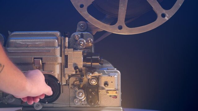 man hand launches an old 16mm film projector. turn on a vintage projector