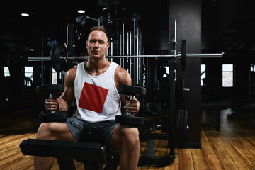 Sport motivation. gym theater. Muscular guy bodybuilder doing exercises with dumbbells in the gym....