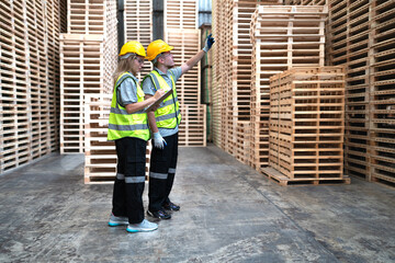 Engineer team standing walking in warehouse examining hardwood material for wood furniture production. Professional technician working on quality control in lumber plank factory. Worker check stock