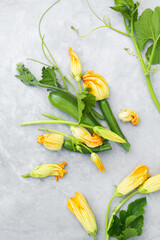 Freshly picked young zucchini with flowers on a gray background. Organic vegetables