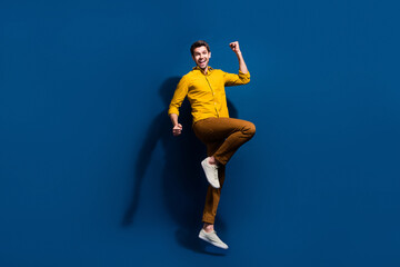 Full body photo of attractive young guy raise fists celebrate dressed stylish yellow clothes...