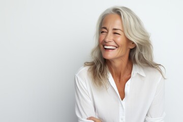 Happy mature woman smiling and looking at the camera while standing against grey background