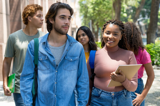 African american female student and hispanic male student walking to university