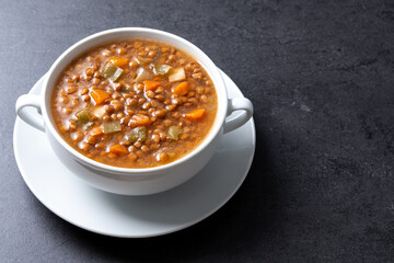 Lentil soup with vegetables in bowl on black background. Copy space