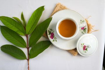 Guava leaf tea in a white cup isolated on White background, herbal drink for diarrhea and cholesterol.selective focus. flat lay angle.