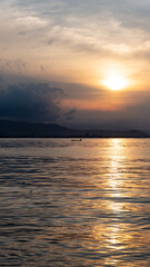 Silhouetted local fishermen in a traditional wooden fishing canoe boat against beautiful golden sunset reflecting over surface of ocean on tropical island of Timor-Leste in Southeast Asia