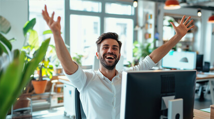 Obraz premium A representative-looking man in the office at the computer with a happy face waves his arms with joy.