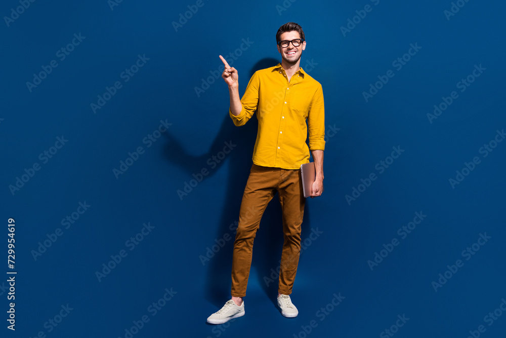 Poster full length photo of nice young male netbook specs point empty space dressed stylish yellow garment 