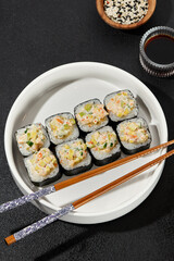 Assorted Sushi Rolls with Shrimp Tartare, Avocado, and Tobiko Caviar on a Modern Dark Surface