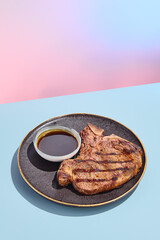 Grilled T-bone beef steak with sauce; a minimalist culinary concept with a surreal summer backdrop