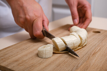 Woman cutting banana into slices close-up of hands - obrazy, fototapety, plakaty