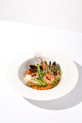 Tomato risotto with seafood on a white plate, perfect for Mediterranean cuisine and healthy eating concepts