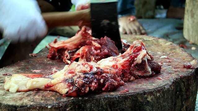 Muslim man chops the bone of slaughtered cow during Eid Al-Adha. The Feast of Sacrifice or Idul Qurban.