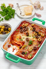 lasagna with olive rings in green baking dish
