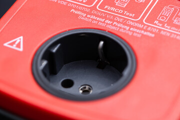 closeup of the power plug of a tester device to measure and prove the safety of electrical applications and utilities, complying to safety regulations in professional businesses