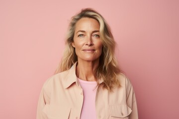 Portrait of mature woman with blonde hair looking at camera over pink background