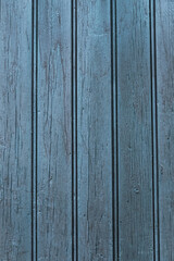 A vertical photograph of old boards painted with blue paint, which has worn out due to time and weather.