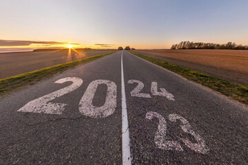 sign 2023, 2024 and start on asphalt road highway with sunrise or sunset sky background.  concept...