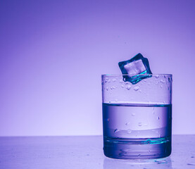 ice cubes falling into glass of water